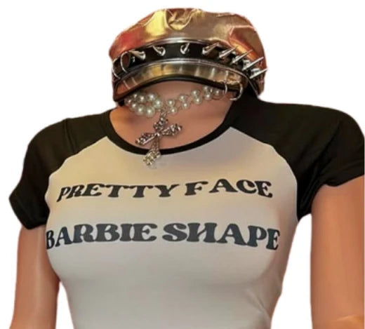 Person wearing a crop top with 'Pretty Face Barbie Shape' text and metallic shorts on a white background.