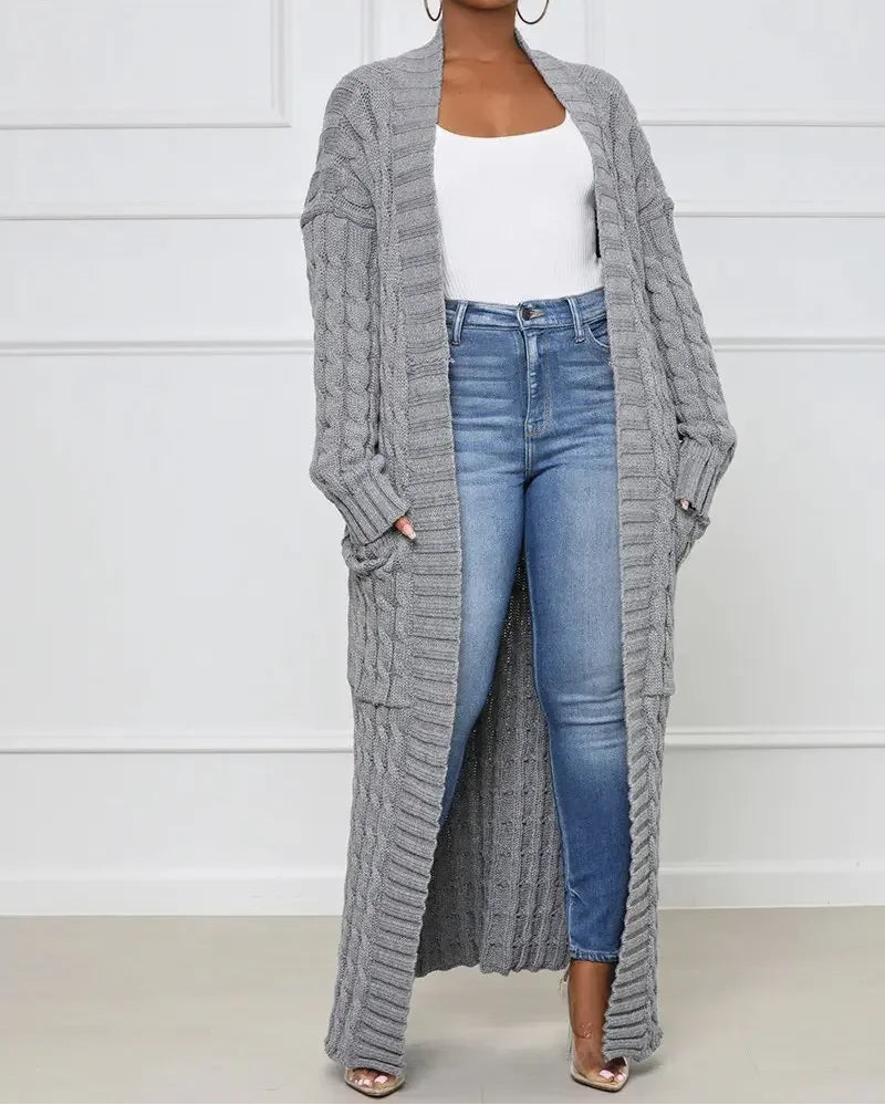 Woman wearing a long gray cardigan, white top, and blue jeans against a white background.