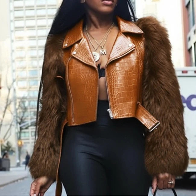 Person wearing a brown leather jacket with fur trim on a city street.