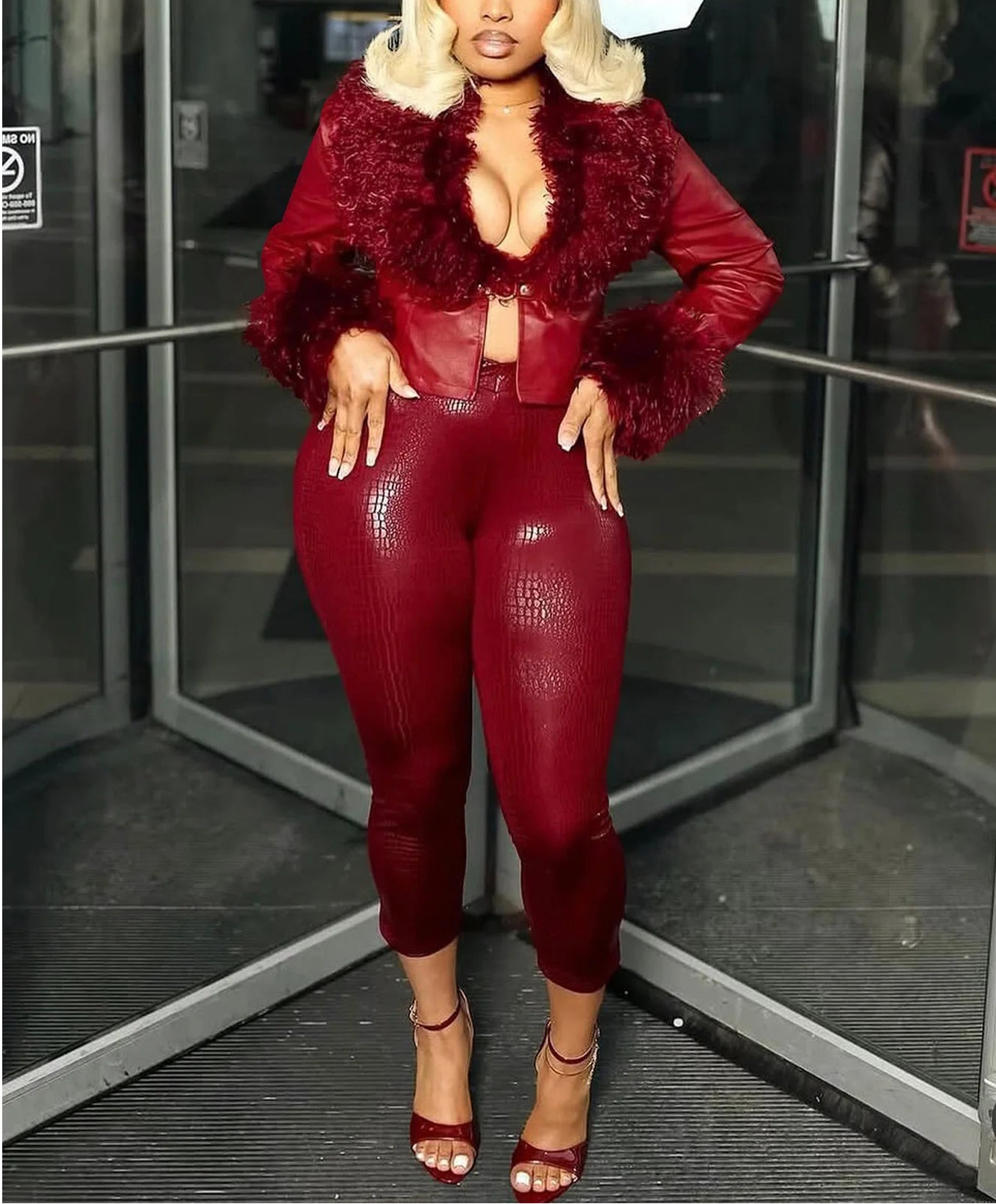 Person wearing a red outfit with a textured jacket in front of glass doors.
