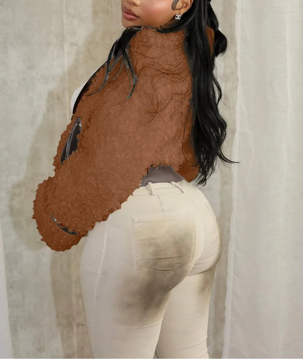 Person wearing a brown textured top and white pants against a neutral background