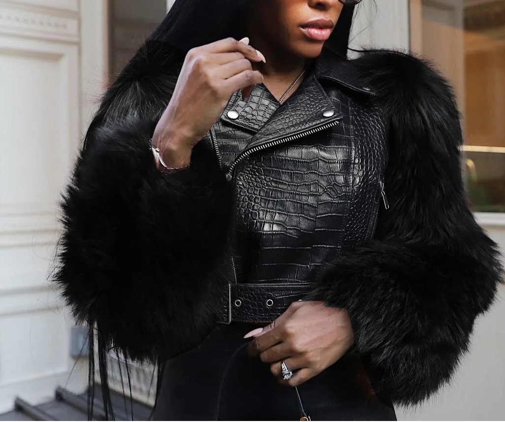 Woman wearing a black leather jacket with fur trim outdoors.