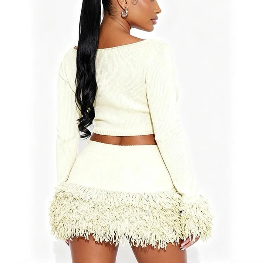 Woman wearing a light-colored outfit with fringe details on a white background, branded 'FAGADOER'.